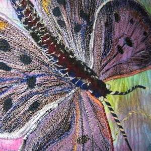 May include: A close-up of a purple and black butterfly embroidered on a fabric background. The butterfly has a detailed design with black and white stitching.