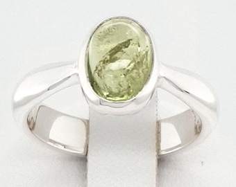 May include: A silver ring with a light green oval gemstone set in a bezel setting.