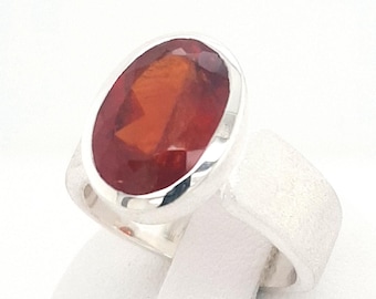 May include: A silver ring with a large, oval-shaped, red gemstone.