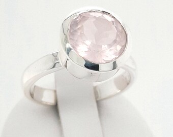 Puede incluir: Un anillo de plata con una gran piedra preciosa redonda de color rosa pálido.