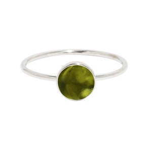 May include: A silver ring with a round green stone set in the center.