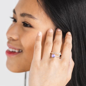 May include: A silver ring featuring a purple stone and a cross design.