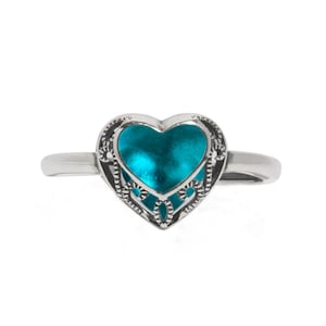 May include: A silver ring with a turquoise heart-shaped charm. The charm has a delicate filigree design.
