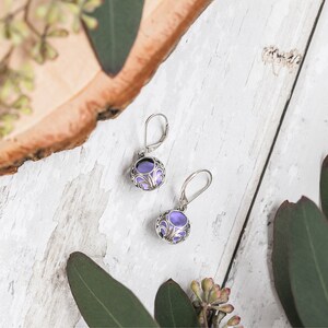 May include: A pair of silver earrings with purple glass stones set in a filigree design.