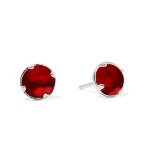 May include: A pair of silver stud earrings with a red round stone in the center.