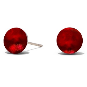 May include: A pair of red stud earrings. The earrings are round and have a smooth, shiny finish.