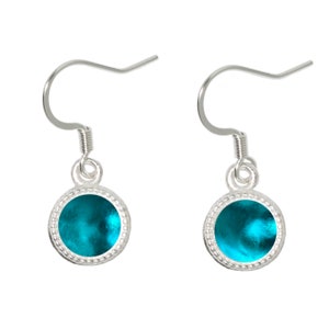 May include: A pair of silver dangle earrings with a turquoise blue round cabochon stone set in a silver bezel.