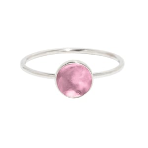 May include: A silver ring with a pink round stone.