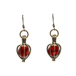 May include: A pair of gold-tone earrings with a red glass bead inside a cage-like design.