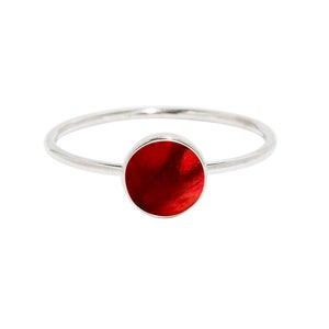 May include: A silver ring with a round red stone set in the center.