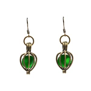 May include: A pair of gold-tone earrings with a green glass bead encased in a cage-like design.