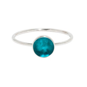 May include: A silver ring with a turquoise blue round gemstone.