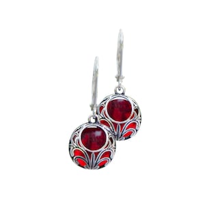 May include: A pair of silver earrings with red glass stones set in a filigree design.