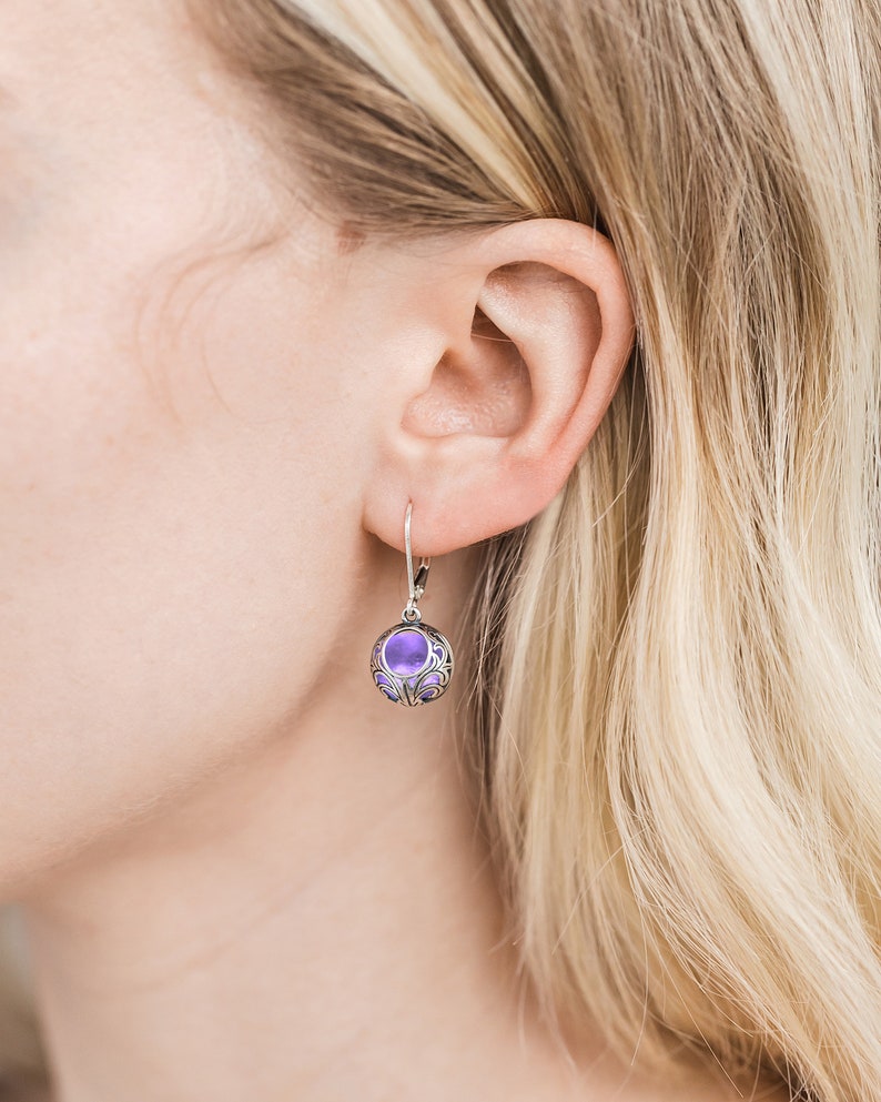 May include: Silver dangle earrings with a purple glass orb in a filigree design.