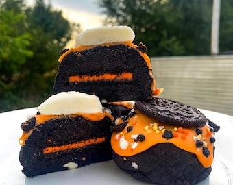 May include: Three chocolate cookies with orange frosting and sprinkles. The cookies are topped with white frosting and Oreo cookies.