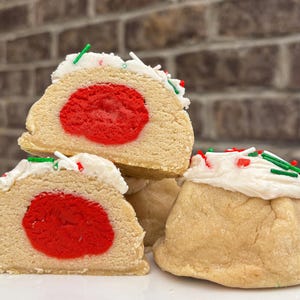 Peut inclure: Gros plan de plusieurs biscuits sur une assiette blanche. Les biscuits sont brun clair avec un centre rouge et un glaçage blanc avec des vermicelles verts et rouges. Les biscuits sont empilés et disposés sur une assiette blanche.