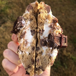 Op de afbeelding: Een chocolade chip cookie gevuld met marshmallow en Hershey's chocolade repen, gebroken in tweeën om de binnenkant te laten zien.