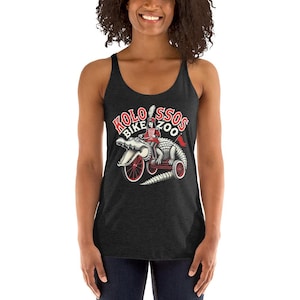 Puede incluir: Camiseta sin mangas gris oscuro con un gráfico de un caimán montando en bicicleta y el texto "Kolossos Bike Zoo" en rojo y blanco. El caimán lleva un sombrero y monta en una bicicleta roja.