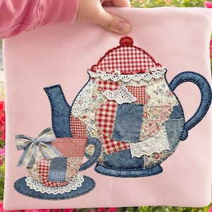 May include: Pink fabric square with a patchwork design of a teapot and teacup. The teapot and teacup are made of denim, floral, and gingham fabrics, with lace accents. The teacup has a bow. The background is a garden with pink flowers.