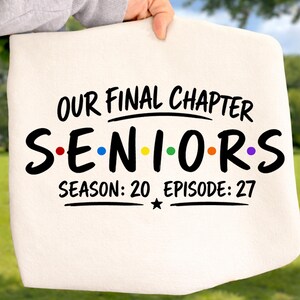 May include: A cream-colored fabric item featuring black text that reads OUR FINAL CHAPTER, SENIORS with colorful dots between the letters, and SEASON: 20 EPISODE: 27 with a small black star below the text, all printed in a bold, sans-serif font.