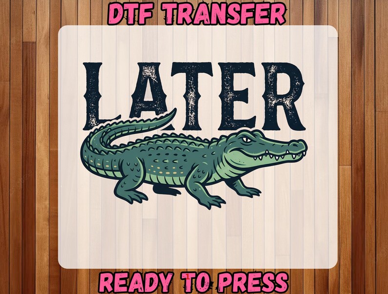 May include: A DTF transfer design featuring the word "LATER" in distressed black font above a green alligator illustration. The words "READY TO PRESS" are below the alligator. The design is on a white background.
