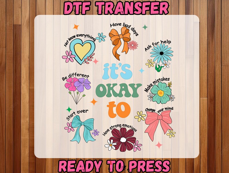 May include: A DTF transfer design with the text "it's OKAY to" in a retro font, surrounded by colorful illustrations of flowers, bows, and phrases like "Have bad days" and "Make mistakes." The words "DTF TRANSFER" and "READY TO PRESS" are also present.