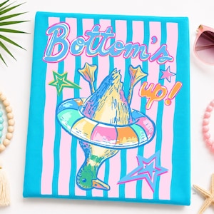 May include: A canvas with a duck illustration wearing a colorful inflatable ring, with the words "Bottom's up!" in a playful font. The background features pink and blue stripes, with star accents.