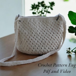 Peut inclure: Un sac en crochet de couleur crème avec une longue bandoulière. Le sac a un motif de point de diamant. Le texte "Crochet Pattern Eng Pdf and Video" est en bas de l'image.