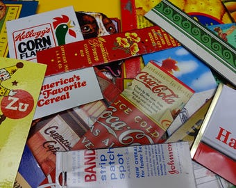 May include: A collection of vintage-style metal signs and advertisements featuring Kellogg's Corn Flakes, Coca-Cola, and Band-Aid branding. The overlapping rectangular pieces display various colorful graphics, logos, and text including America's Favorite Cereal.