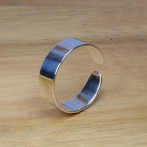 Peut inclure: Une bague ajustable en argent avec une surface lisse et plate.