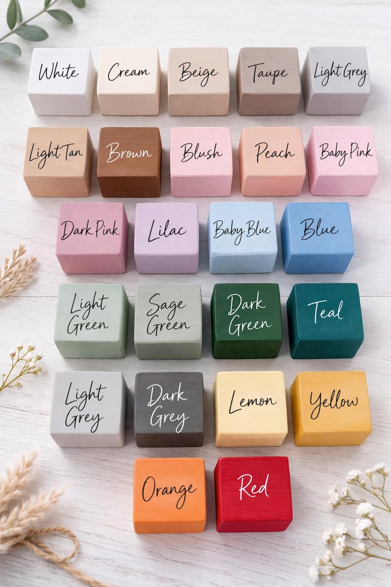 Pode incluir: Uma cole&ccedil;&atilde;o de vinte e quatro pequenos blocos de madeira quadrados, cada um pintado de uma cor diferente e rotulado com o nome da cor em escrita cursiva. As cores incluem branco, creme, bege e v&aacute;rias tonalidades de rosa, verde e cinza.