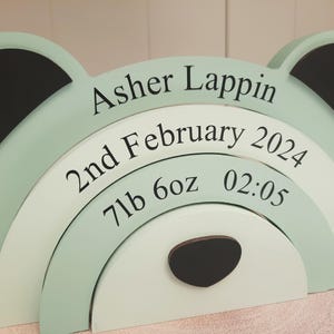 May include: A layered wooden bear-shaped sign in pastel green and white, with black accents. The sign displays the name "Asher Lappin", birthdate, weight (7lb 6oz), and time (02:05) in black text, perfect for a nursery or baby's room.