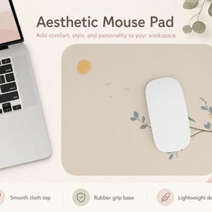 May include: A rectangular mouse pad with a beige surface featuring a minimalist illustration of a yellow sun, small birds, and a branch with blue leaves. A white computer mouse rests on the pad, which is positioned next to a laptop computer.