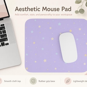 May include: A rectangular mouse pad with a light purple background featuring a pattern of small yellow and light blue stars. A white computer mouse rests on the surface of the pad, which is positioned next to a silver laptop computer.