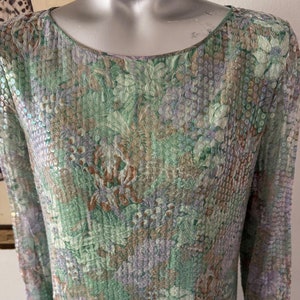 May include: A long-sleeved, green, floral patterned dress with sequins. The dress has a round neckline and a loose fit.