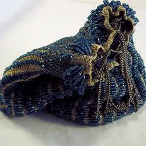 Può includere: Una borsa a tracolla in perle blu e beige con una catena. La borsa è realizzata con piccole perle rotonde e ha una chiusura a coulisse.