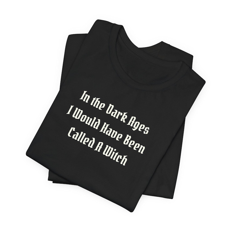 May include: Black t-shirt with white text that reads "In the Dark Ages I Would Have Been Called A Witch".