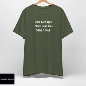May include: A dark green t-shirt with the text "In the Dark Ages I Would Have Been Called A Witch" printed in white.