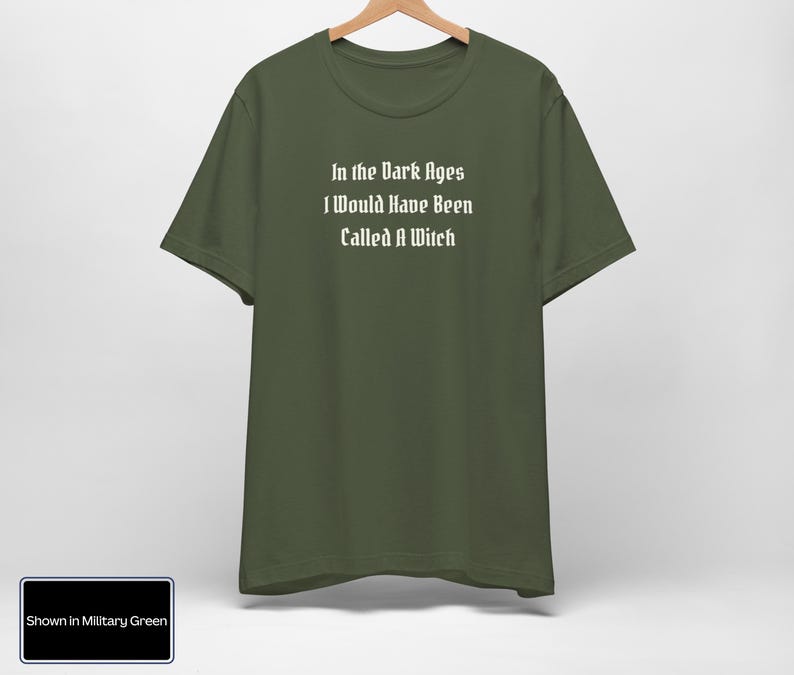 May include: A dark green t-shirt with the text "In the Dark Ages I Would Have Been Called A Witch" printed in white.
