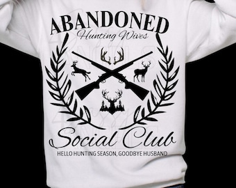 Op de afbeelding: Wit sweatshirt met een zwart grafisch ontwerp. Het ontwerp bevat gekruiste geweren, silhouetten van herten en de tekst "ABANDONED Hunting Wives Social Club". De zin "HELLO HUNTING SEASON, GOODBYE HUSBAND" staat er ook op.