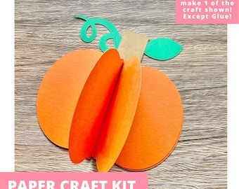 May include: A paper craft kit featuring pre-cut orange circular shapes to assemble a 3D pumpkin, a green paper vine, a green leaf, and a brown rectangular stem. The text on the image reads: Includes everything needed to make 1 of the craft shown! Except Glue! PAPER CRAFT KIT PRE-CUT CRAFTS FOR KIDS