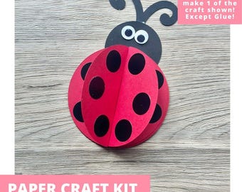 May include: A paper craft kit featuring a ladybug made from red and black cardstock with googly eyes. The text on the image reads: Includes everything needed to make 1 of the craft shown! Except Glue! and PAPER CRAFT KIT PRE-CUT CRAFTS FOR KIDS.
