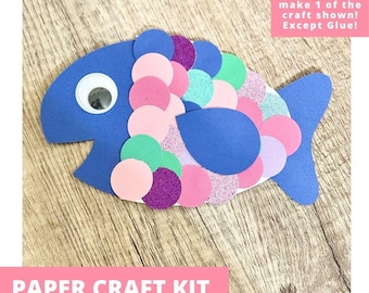 May include: A blue paper fish craft kit featuring a googly eye and numerous overlapping circular scales in shades of pink, purple, green, and blue. Some scales have a glittery texture. The kit includes materials to make one fish, excluding glue.