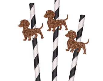 May include: Three drinking straws featuring a black and white diagonal striped pattern. Each straw is decorated with a brown glittery cutout of a dachshund dog silhouette attached to the upper portion of the paper straw structure.