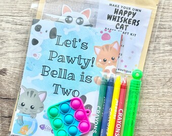 May include: A craft kit in a clear plastic bag containing a card with cat illustrations and the text Let's Pawty! Bella is Two, a Make Your Own Happy Whiskers Cat label, four colored crayons, a small square pop-it toy, and a green bubble wand.