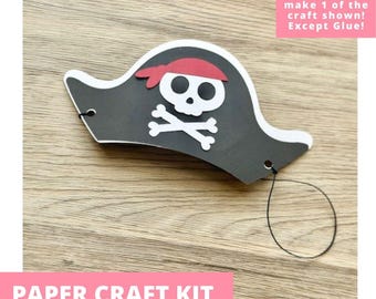 May include: A black paper pirate hat craft with a white skull and crossbones design and a red headband detail. The hat features two small holes on the sides with a thin black elastic string attached for wearing, designed as a pre-cut paper craft kit.