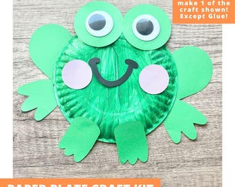May include: A paper plate craft kit featuring a green frog design with large googly eyes, pink paper cheeks, and a black paper smile. The kit includes pre-cut green paper limbs and body parts. Text on the image reads: Includes everything needed to make 1 of the craft shown! Except Glue! PAPER PLATE CRAFT KIT PRE-CUT CRAFTS FOR KIDS.