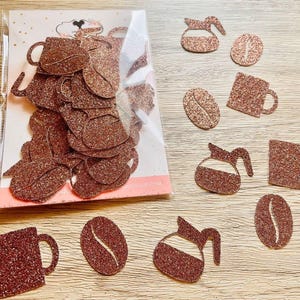 May include: A collection of copper-colored glitter die-cut shapes including coffee mugs, coffee pots, and coffee beans. Some shapes are contained within a clear plastic sleeve on a white backing card, while others are scattered individually.