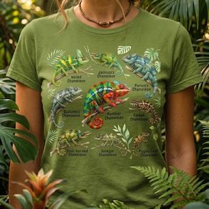 May include: A green t-shirt displaying a detailed illustration of different chameleon species, such as Veiled, Jackson's, and Panther chameleons. Each species is labelled. The shirt is a short-sleeved crew neck.