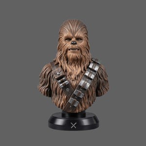 May include: A brown, fur-covered Wookiee bust featuring a detailed face with visible teeth and eyes. The figure wears a dark brown leather bandolier with metallic silver accents across the chest. It is mounted on a black circular base with an X symbol.